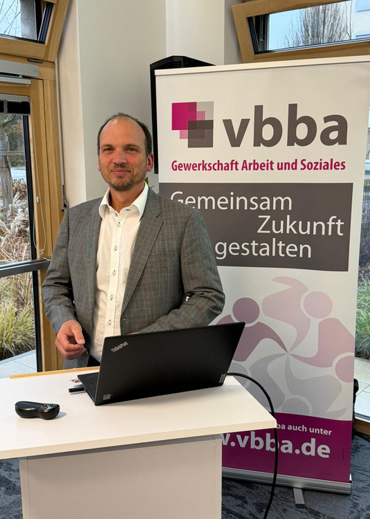 Mario Döll am Rednerpult mit Laptop, dahinter das vbba Roll up.