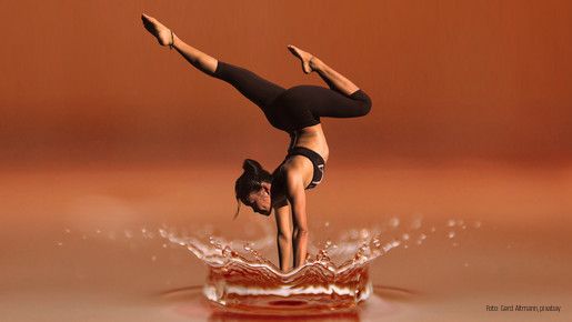 Eine Frau macht einen Handstand im flachen Wasser