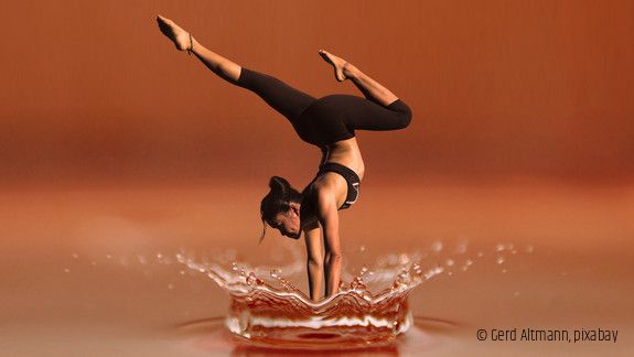Eine Frau macht einen Handstand im flachen Wasser